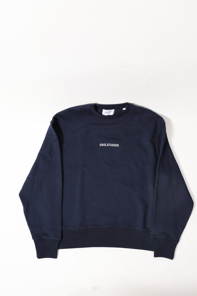 Folded navy blue sweatshirt with a brand label on a white background